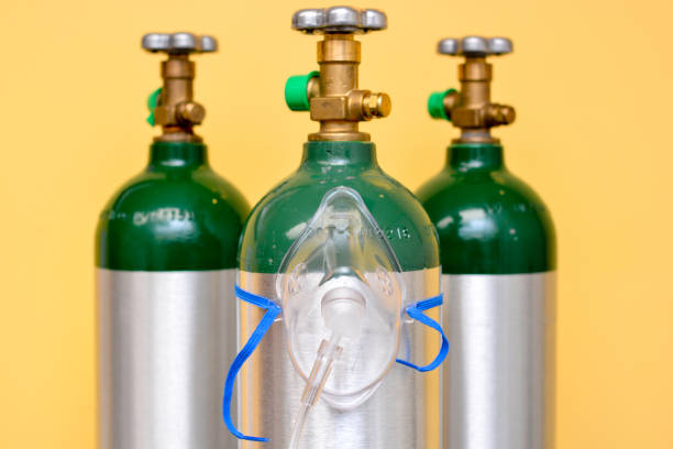 3 Medical Oxygen Tanks with Oxygen Mask 3 medical oxygen tanks on yellow background with oxygen mask on the center cylinder. oxygen photos stock pictures, royalty-free photos & images