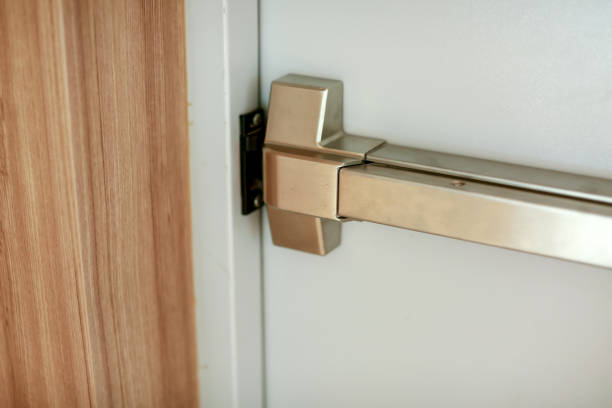 istock Emergency fire exit door. Closed up latch and rusty door handle of emergency exit. Push bar and rail for panic exit. Open one way door.  steel of handle for the white door fire exit 1297985713