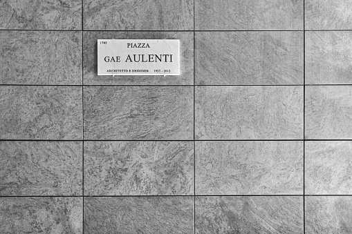 Natural grey granite texture tile wall with sign - Piazza Gae Aulenti, architetto e designer - which means Gae Aulenti square, architector and designer. December 17, 2020 - Milan, Italy