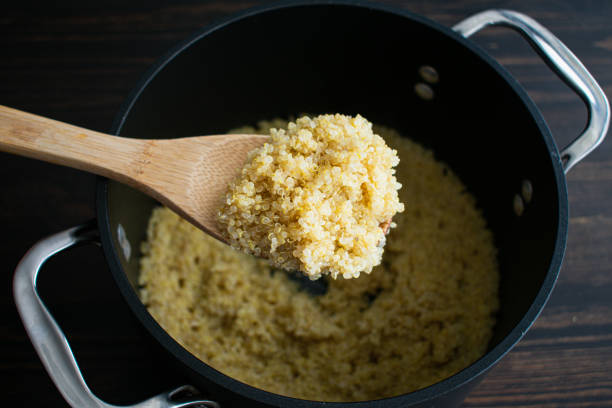 a spoonful of cooked quinoa - quinoa spoon wood photography imagens e fotografias de stock