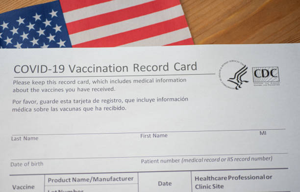 Fragment of COVID-19 Vaccination Record card form by CDC on Flag of USA Background. stock photo