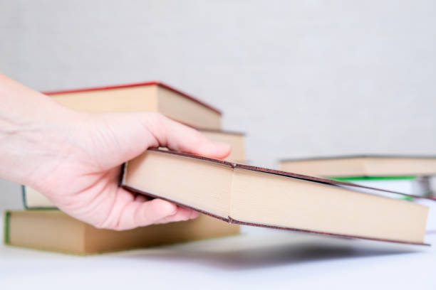istock A hand taking a book from a stack, pile, choosing and selecting books for reading and education 1297996737