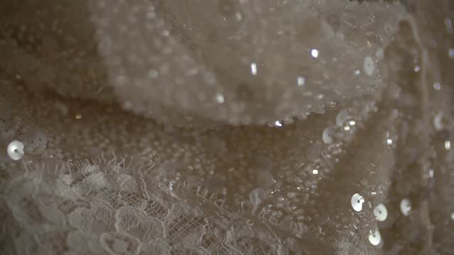 Thin light lace of a wedding dress, embroidered with sequins and sparkling beads