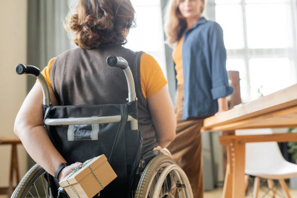 istock Young disable businesswoman hiding giftbox with birthday present behind her back 1297998331