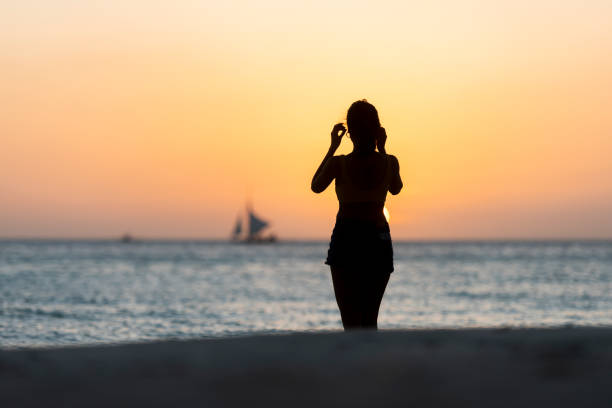 (mise au point sélective) vue renversante de la silhouette d’une fille marchant sur une plage pendant un coucher de soleil beau et romantique. white beach, boracay island, philippines. - people traveling elegance philippines palawan photos et images de collection