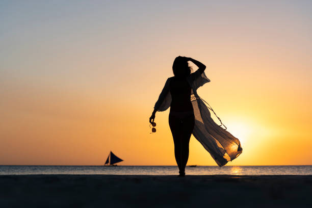 (mise au point sélective) vue renversante de la silhouette d’une fille marchant sur une plage pendant un coucher de soleil beau et romantique. white beach, boracay island, philippines. - people traveling elegance philippines palawan photos et images de collection