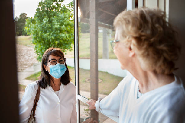 starsza kobieta otwierająca drzwi dla pielęgniarki w domowej opiece zdrowotnej - nursing home senior adult home caregiver physical therapy zdjęcia i obrazy z banku zdjęć