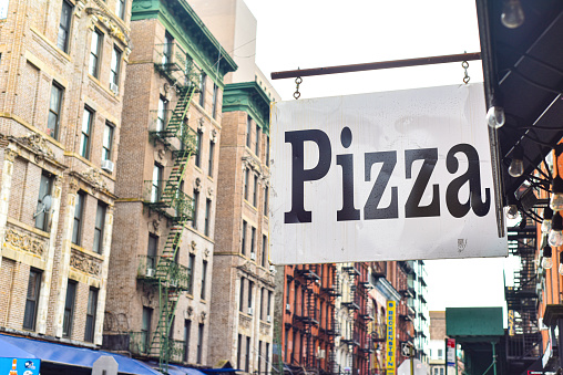A pizza sign hanging outside a restaurant in new york city