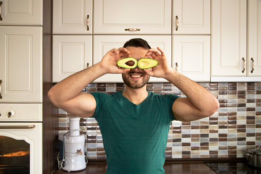 Young man with avocado on his eyes smiling