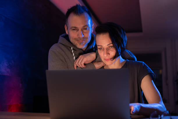 istock Man and woman browsing internet on laptop at night 1298002954