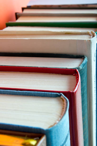 istock Open hardback book on wooden deck table and red background 1298003007