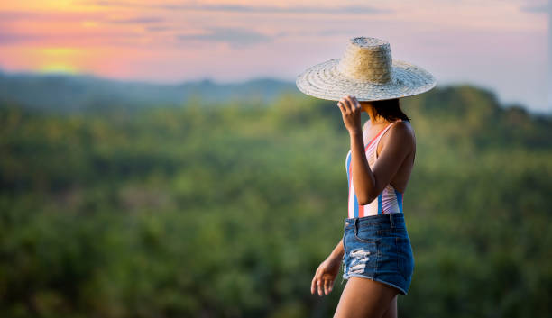 (Selective focus) Stunning view of a girl with a large straw hat admiring the palm tree forest is Siargao, Philippines. (Selective focus) Stunning view of a girl with a large straw hat admiring the palm tree forest is Siargao, Philippines. Siargao is a tear-drop shaped island in the Philippine Sea. summer fashion philippines palawan stock pictures, royalty-free photos & images