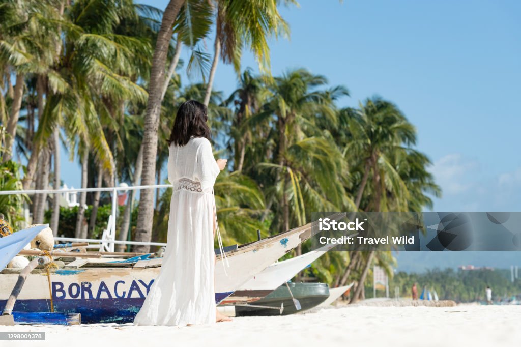 (Selective focus) Stunning view of a girl dressed in white, walking on a beach during a beautiful sunny day. White Beach, Boracay Island, Philippines. Boracay Stock Photo