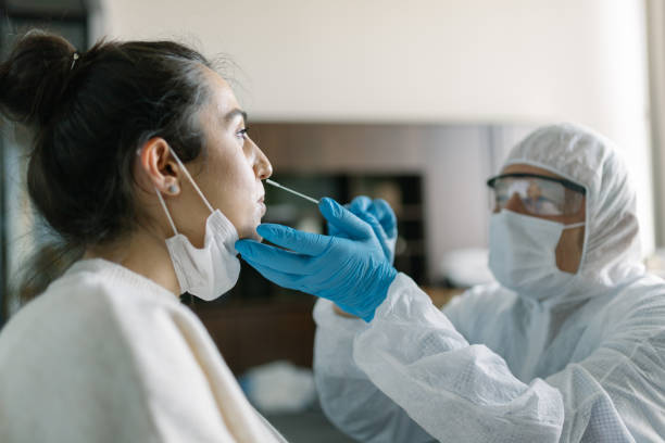 Doctor in protective workwear taking nose swab test from young woman Doctor in protective workwear taking nose swab test from young woman pcr device photos stock pictures, royalty-free photos & images