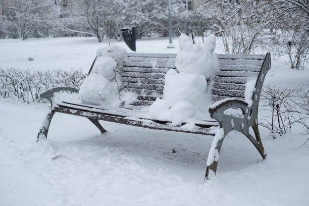 istock Funny snowman sitting on park bench 1298006510