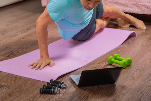 istock 50 year old man performs exercises lying on mat at home looking at computer 1298009813
