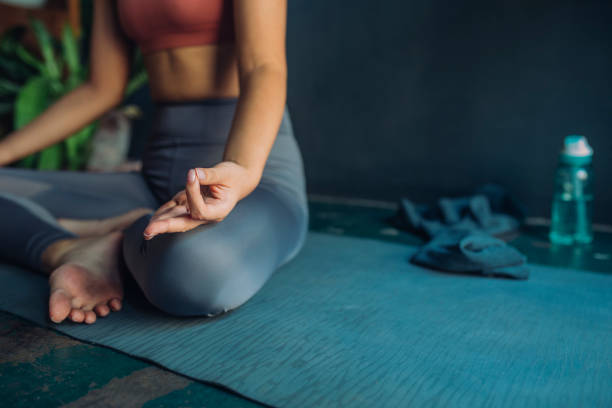 istock Anonymous Woman Sitting on a Yoga Mat and Meditating 1298010162