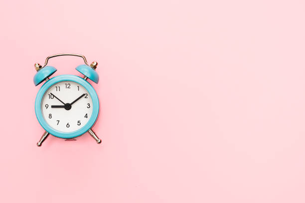 istock Classic blue alarm clock on a pink background. 1298013582