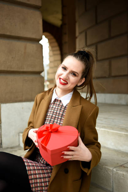 istock young woman holding a heard gift box 1298014523