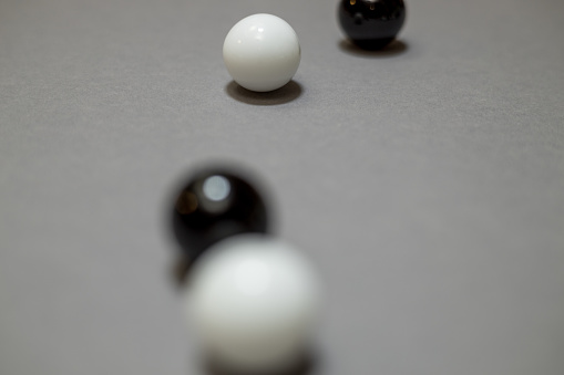 Black and white balls rolling and colliding randomly on the gray surface