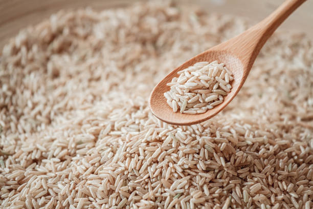 riso integrale in cucchiaio di legno o bambù - brown rice rice healthy eating organic foto e immagini stock
