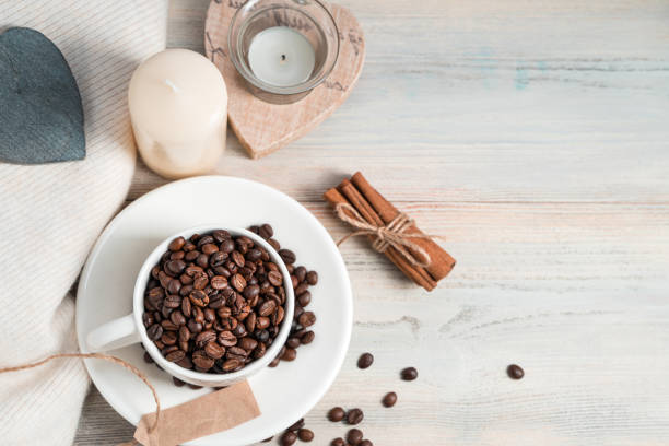 Coffee background with coffee beans in a Cup and candles on a light cozy background with space for copying. Cafe concept.