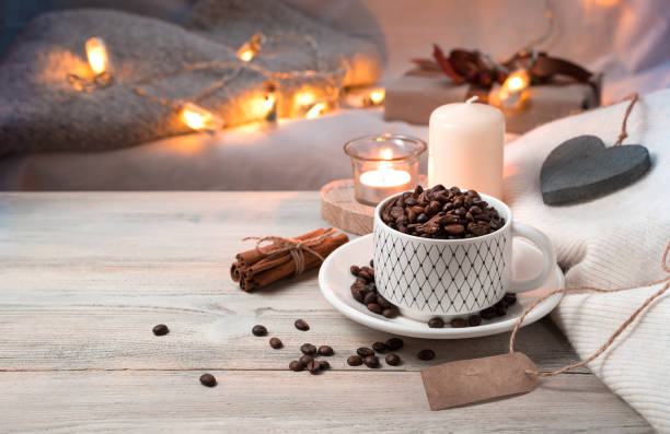 A Cup of coffee full of coffee beans on a cozy evening holiday background with lights