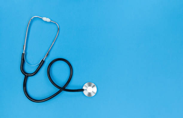 istock Black stethoscope on blue background. Simple flat lay with copy space. 1298022534