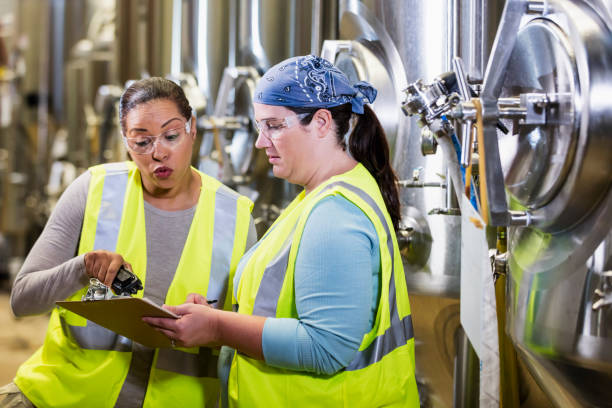 istock Two women working in factory looking at clipboard 1298022791