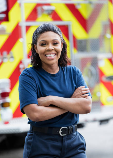 istock Female firefighter standing in front of fire truck 1298022822