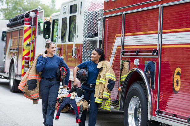 istock Two female firefighters walking next to fire trucks 1298023374