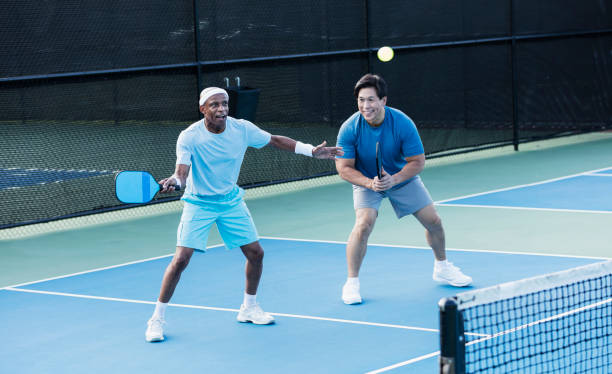 starsi mężczyźni grają w paddleball, uderzając piłkę - mixed doubles zdjęcia i obrazy z banku zdjęć