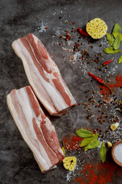 raw pork belly with skin and spices and herbs on dark background. - pancetta imagens e fotografias de stock