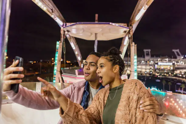 Photo of Young African-American couple riding ferris wheel