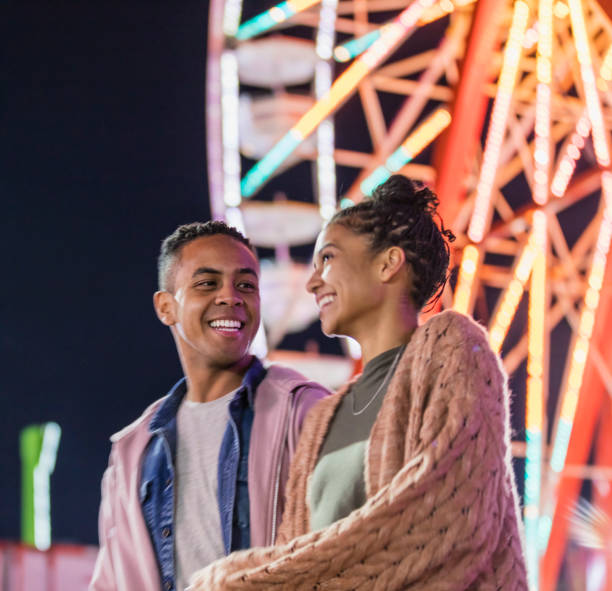 istock Young couple at county fair, by ferris wheel 1298023618