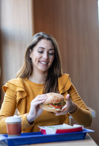 istock Young woman on lunch break, eating burger. 1298024364