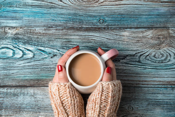 istock Women's hands hold a round ceramic Cup with a hot coffee drink on a wooden background 1298025594