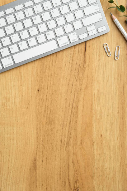 Flat lay, top view modern office desk table with computer keyboard, stationery, eucalyptus leaf on wooden background. Minimal style freelancer workspace