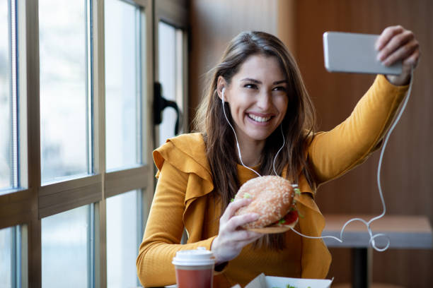 istock Girl holds burger, taking selfie. 1298027833