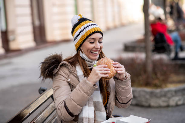 istock Girl enjoying burger, sitting on bench. 1298028696
