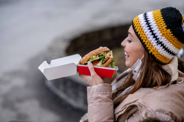 istock Girl in knit hat is eating burger. 1298029245