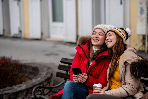 istock Friends sitting on street bench, looking in front of them. 1298030881