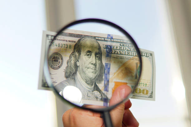 istock Hundred dollar bill under magnifying glass is being inspected Conceptual photo on window background 1298030941