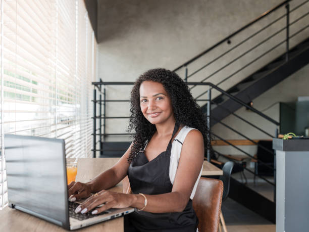 istock Entrepreneurial woman with apron working on computer in a coffee shop 1298031013