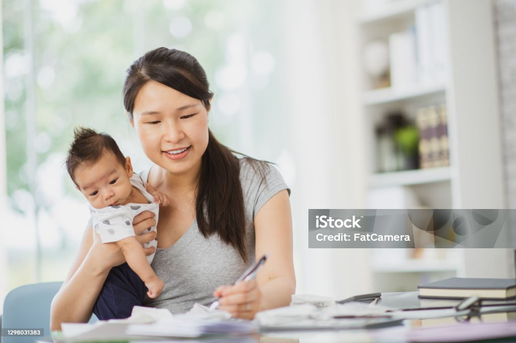 Juggling work and childcare at home A new mother and business owner is juggling work and childcare while at home. Maternity Leave Stock Photo