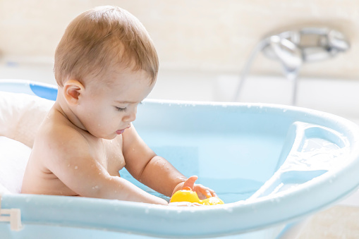A cute baby is bathing in the tub.