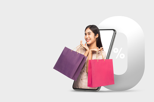 Young smiling beautiful asian woman making online shopping with 0 % interest installment payment promotion and holding shopping bags out through mobile phone.