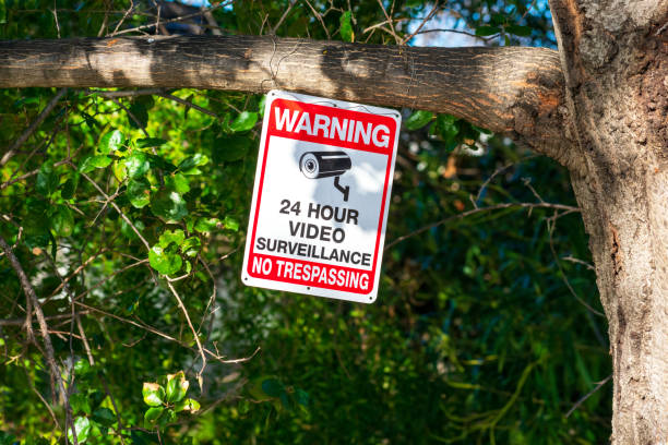istock Warning, no trespassing, 24 hour video surveillance, security camera sign on tree trunk 1298043825