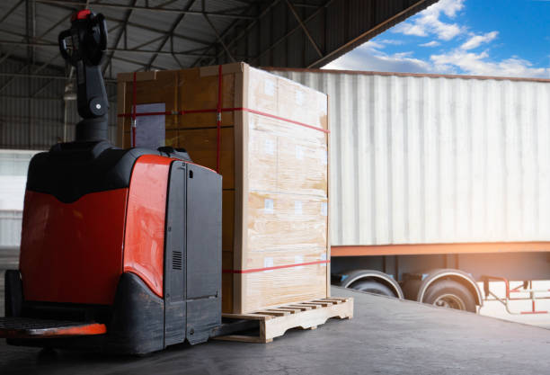 istock Cargo shipment loading for truck. Electric forklift pallet jack loading heavy cargo pallet into container truck. dock warehouse. Logistics. Freight truck transportation. 1298048023