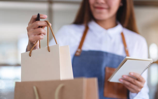 istock A beautiful young female entrepreneur with apron checking orders from customer 1298048741